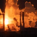 Air pollution and global warming. Smoking chimneys of thermal power plant at sunset in winter city