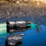 Closeup image of soil polluted with plastic gardage and oil waste. Concept of harm to environment