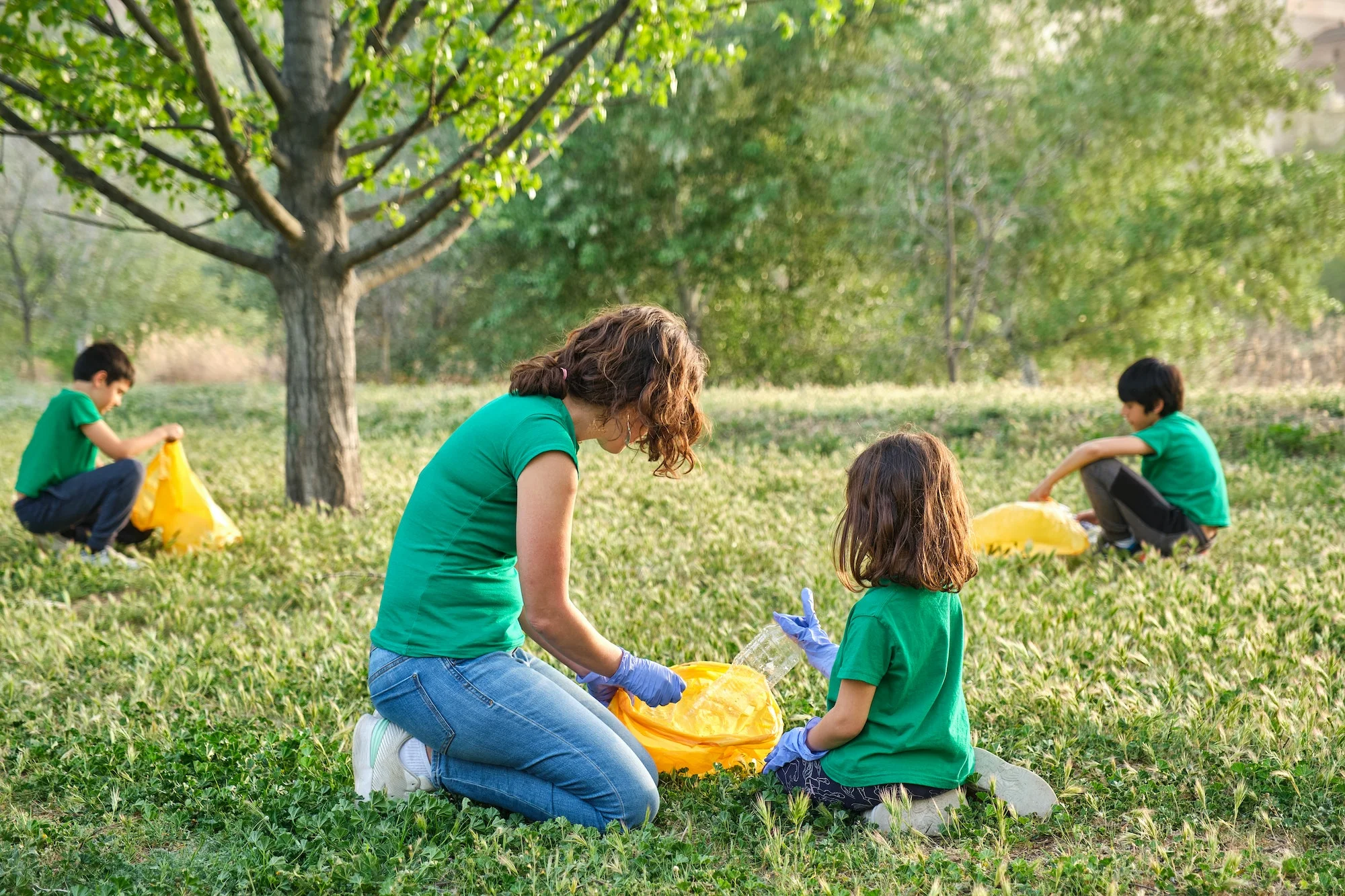 family in a green area with grass and trees collecting garbage and plastic from the countryside