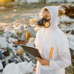 Researcher looking at plastic landfill analyzing environmental pollution level