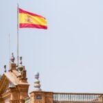 The flag of Spain flies over the building at the Plaza de España in Seville